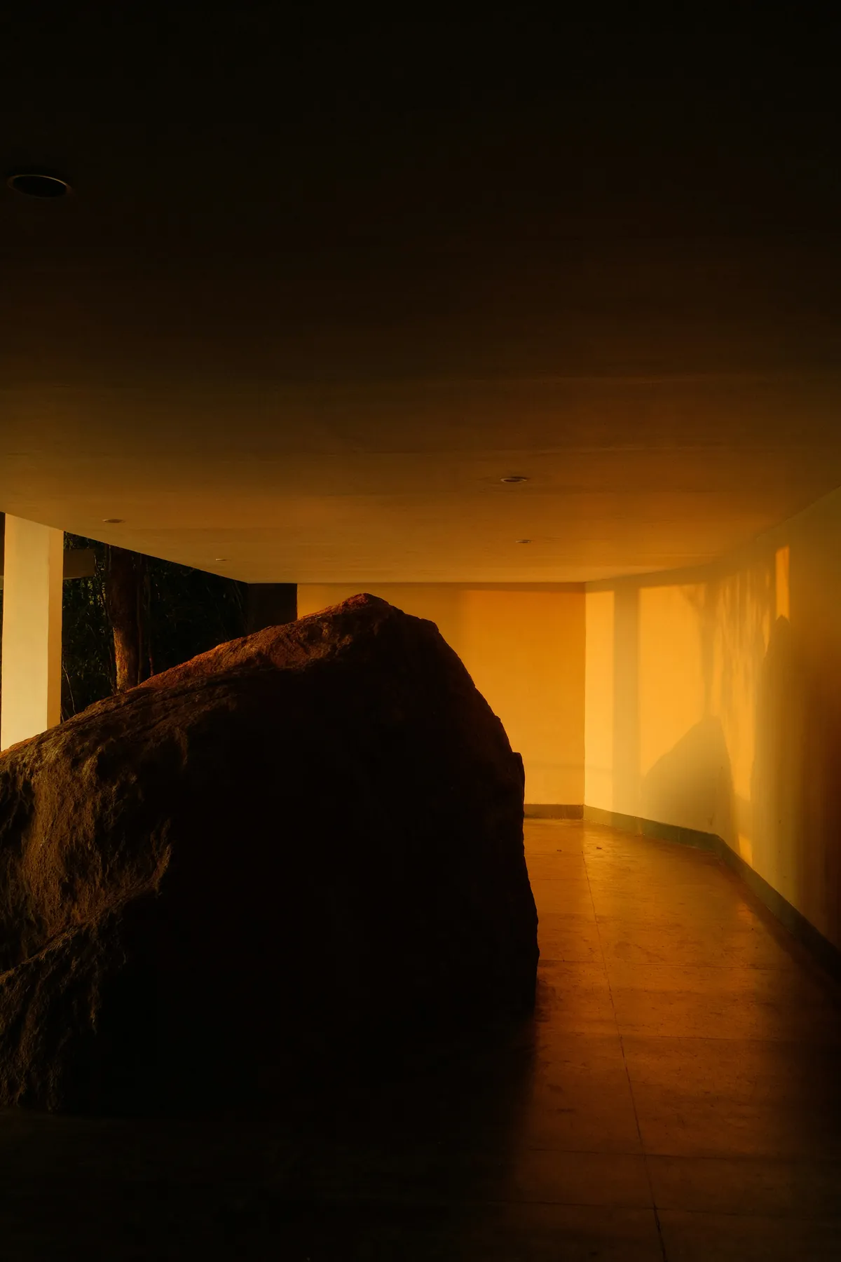 An amber-lit room with a stone form in the foreground.